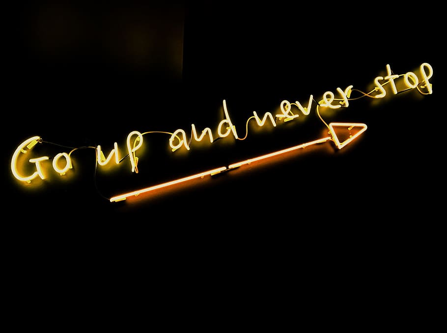 black background with yellow text overaly, yellow Go up and never stop neon signage