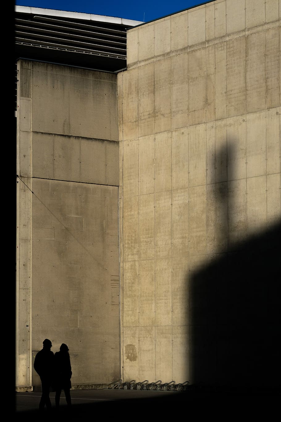 two silhouette of person standing near wall, two persons standing near brown wall HD wallpaper