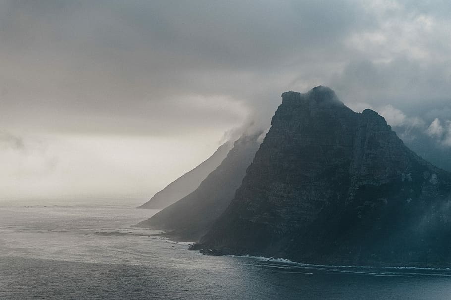 aerial photography of rock mountain island with ocean water view during daytime, photo of mountains beside calm body of water HD wallpaper
