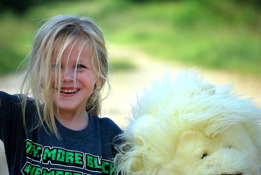 Girl wearing black printed shirt standing beside white lion plush toy, HD wallpaper