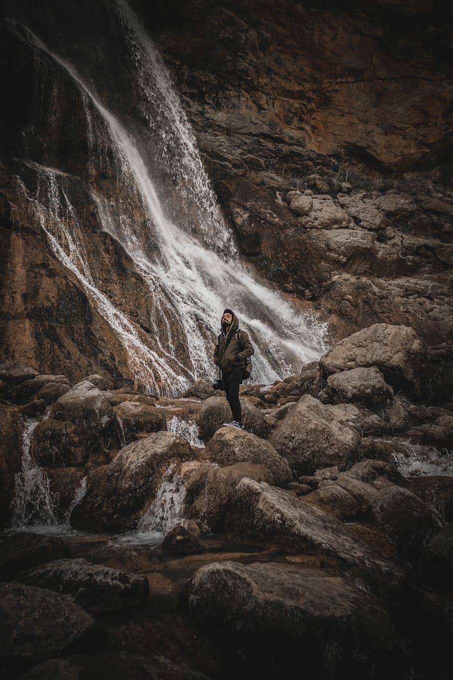 HD wallpaper: man standing near waterfall, photo of man wearing brown ...
