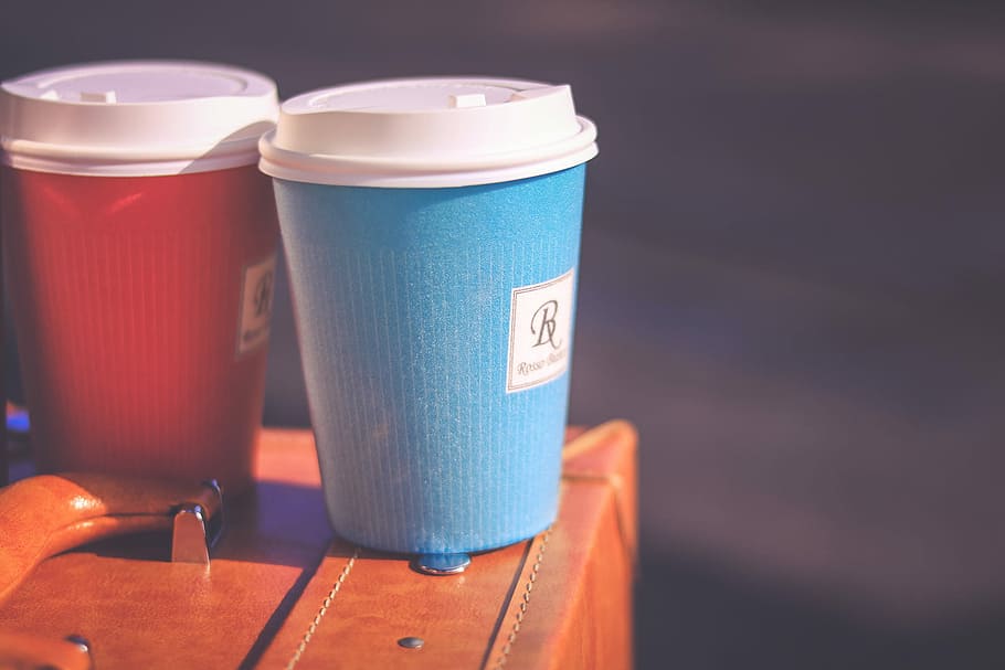 two blue-white-and-red coffee cups on brown leather briefcase