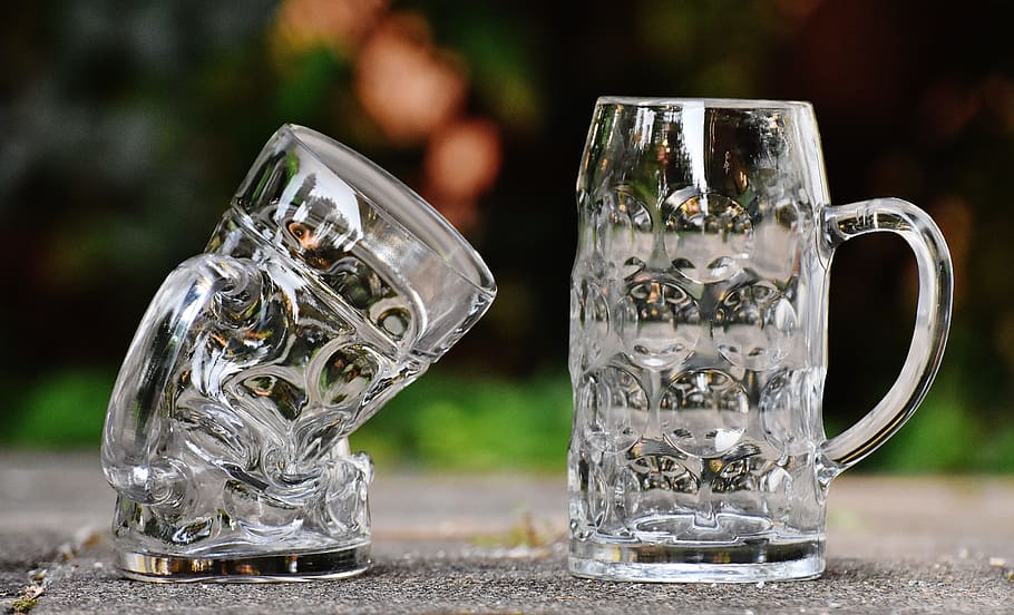 two clear glass beer mugs on gray surface, deformed, kink, funny