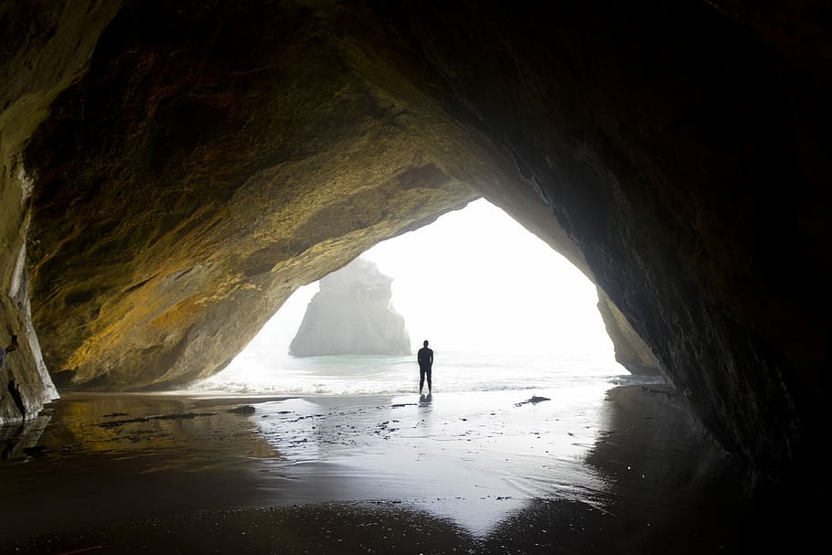 photography of person standing in cove, silhouette on man in cave HD wallpaper