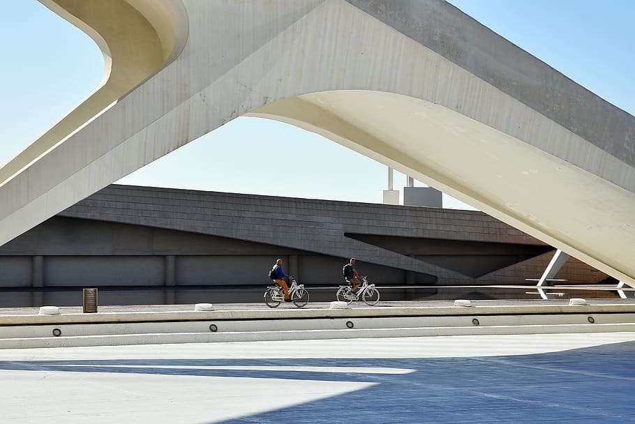 two people riding bikes near wall under blue sky, modern, architecture HD wallpaper