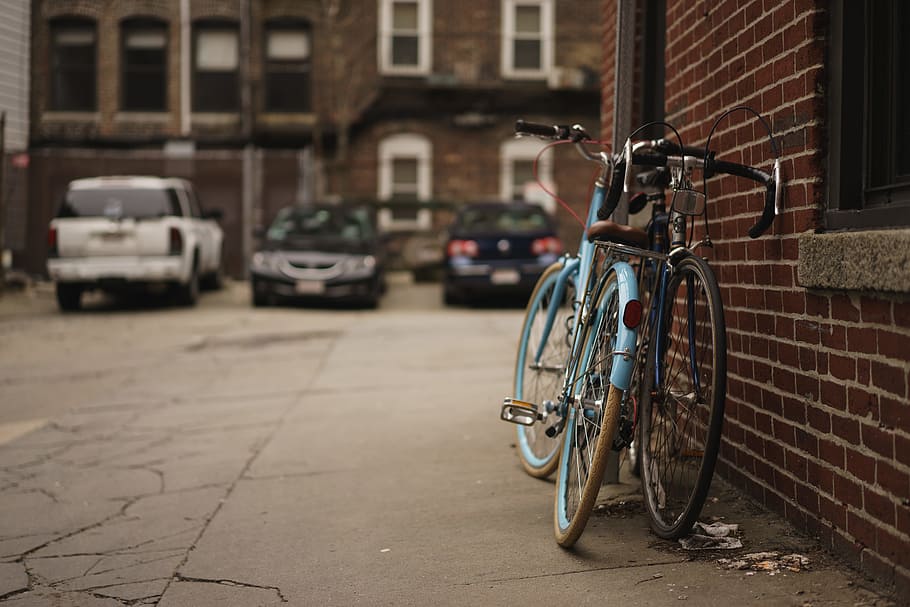 two blue city bikes, two teal and black leaning on brown brick wall at daytime, HD wallpaper