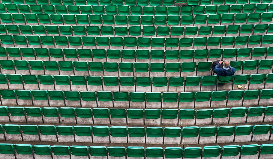 man sitting on bleachers, person sitting on green chairs, seats