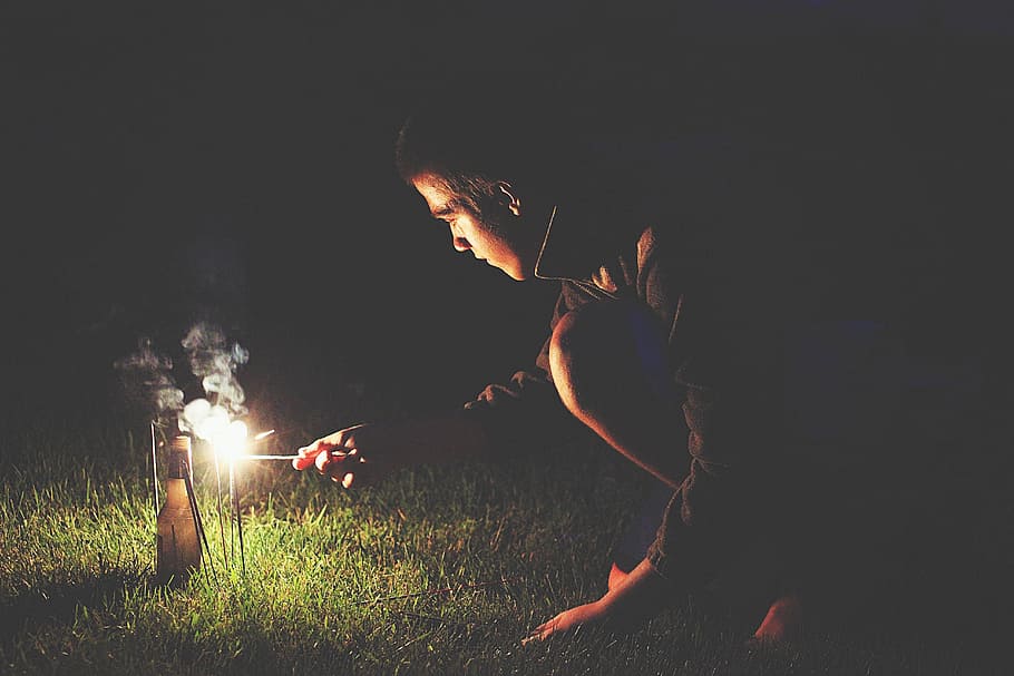 man crouching holding sparkler, man holding lamp, man in black HD wallpaper