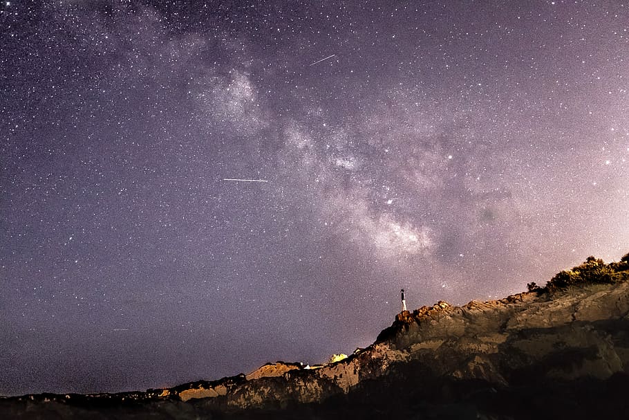 person standing on rock formation under starry sky, person standing on mountain under starry night HD wallpaper