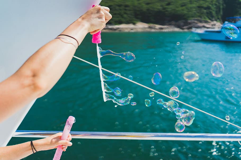 person playing with bubbles during daytime, person playing bubbles near body of water HD wallpaper