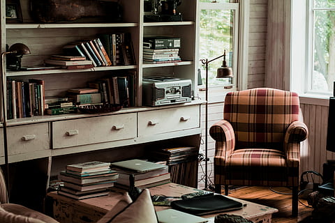 books on table, brown and black plaid armchair near white wooden bookshelf HD wallpaper