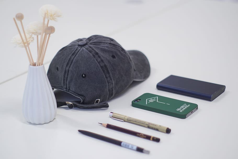 gray fitted cap, three pen, smartphone, and blue power bank on white surface, gray cap on white surface HD wallpaper