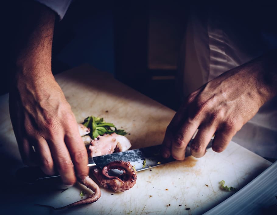person slicing squid, hands, cutting, cooking, knife, chopping board