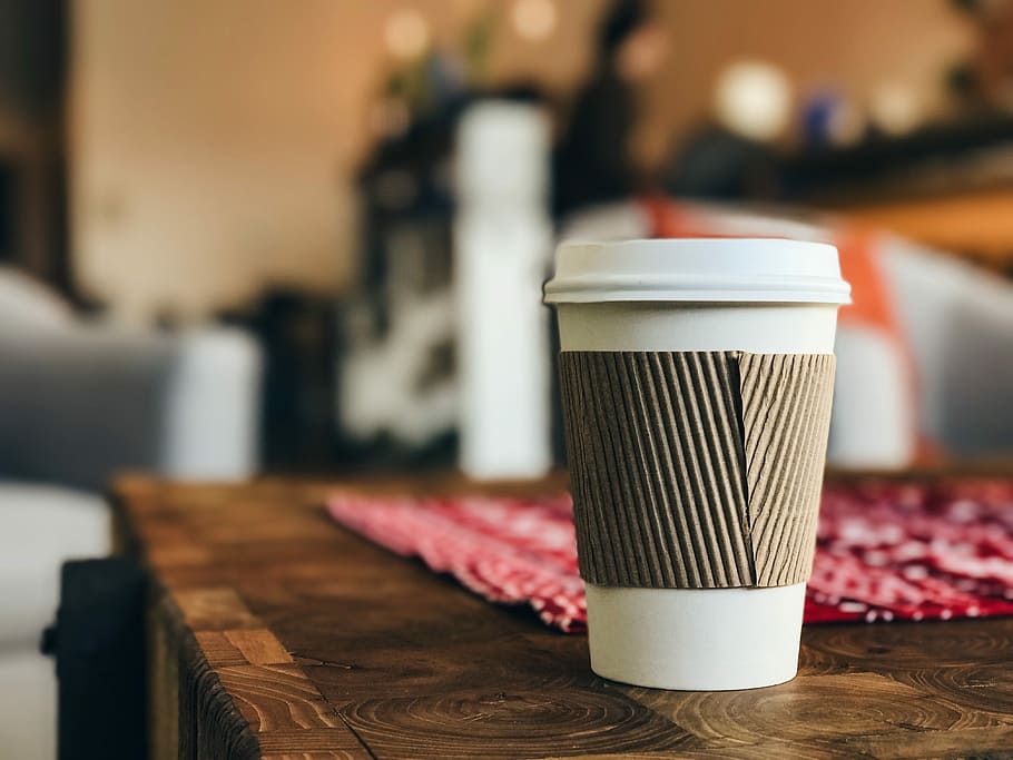 white plastic cup on brown surface, white and gray disposable coffee cup on top of brown wooden table