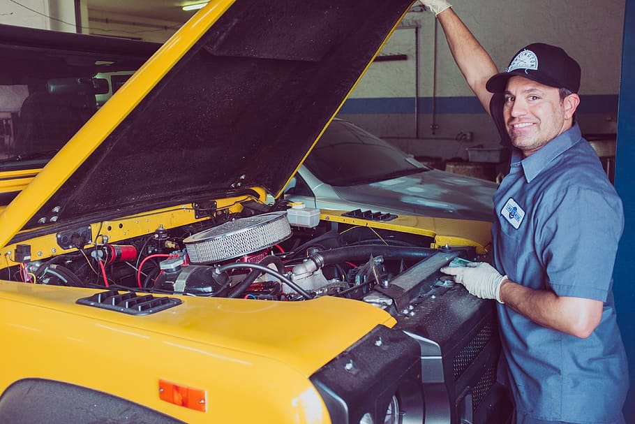 man holding open-wide car trunk, smiling man repairing yellow vehicle HD wallpaper