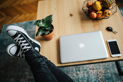 Woman in ripped jeans and black sneakers with a silver laptop on a wooden table HD wallpaper