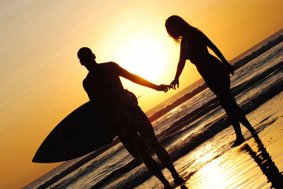 silhouette of woman and man, sunset, beach, surfing, holding hands HD wallpaper