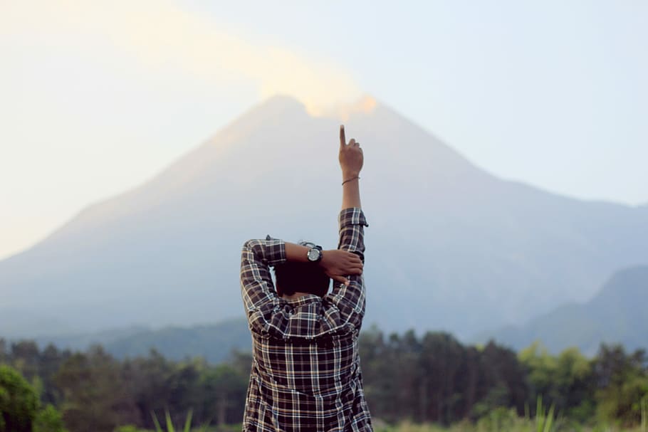 man raising right hand, pointing, up, mountain, volcano, one person HD wallpaper