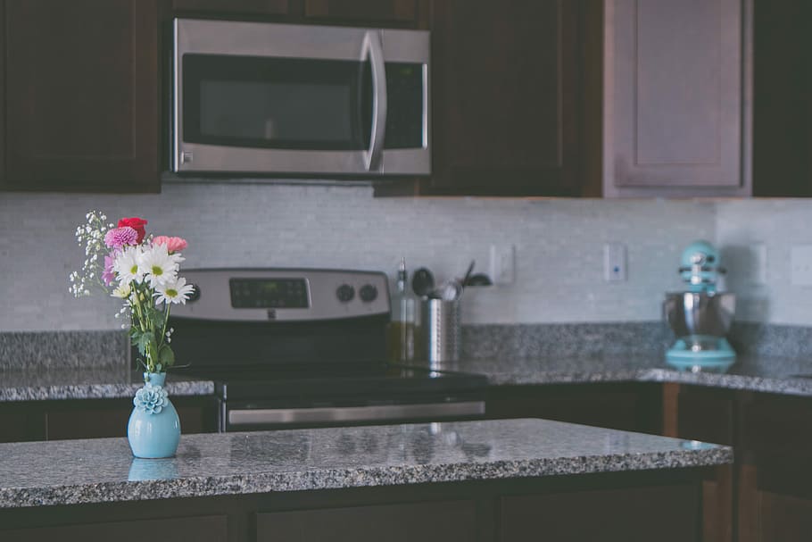 flower arrangement on vase on kitchen island, silver wall-mount microwave oven over electric smooth top range HD wallpaper