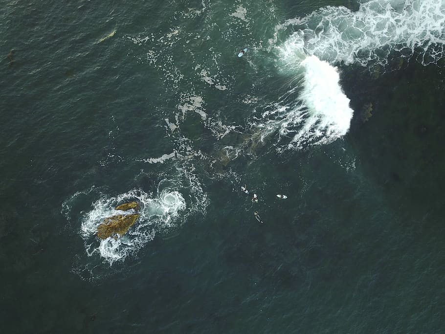 aerial photo of body of water during daytime, brown rock formation in middle of ocean at daytime HD wallpaper