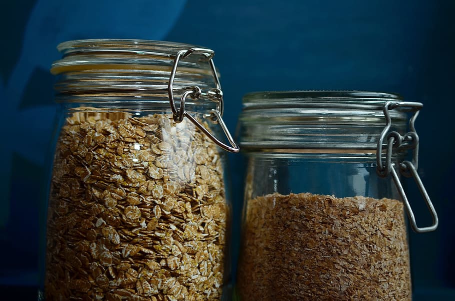 close up photo of two clear canister jars, cereals, spelt flakes