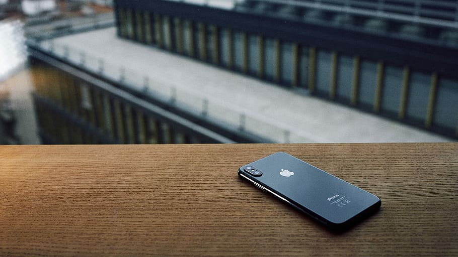 focus photo of space gray iPhone X on brown wooden table, selective focus photography of space gray iPhone X placed on brown surface HD wallpaper