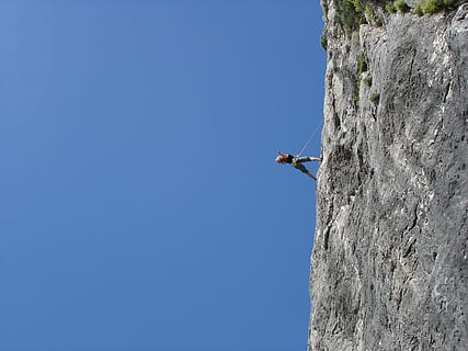 person in black top and grey shorts rock climbing during daytime HD wallpaper