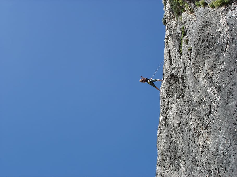 person in black top and grey shorts rock climbing during daytime HD wallpaper