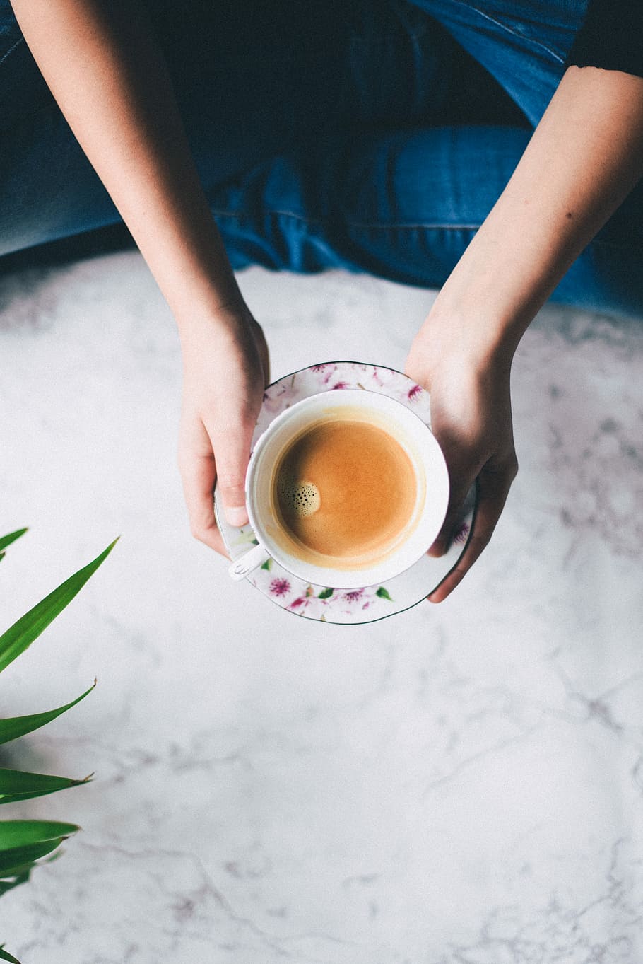 flat-lay photography of person holding teacup, person holding white ceramic cup filled with brown liquid on white and pink floral saucer HD wallpaper
