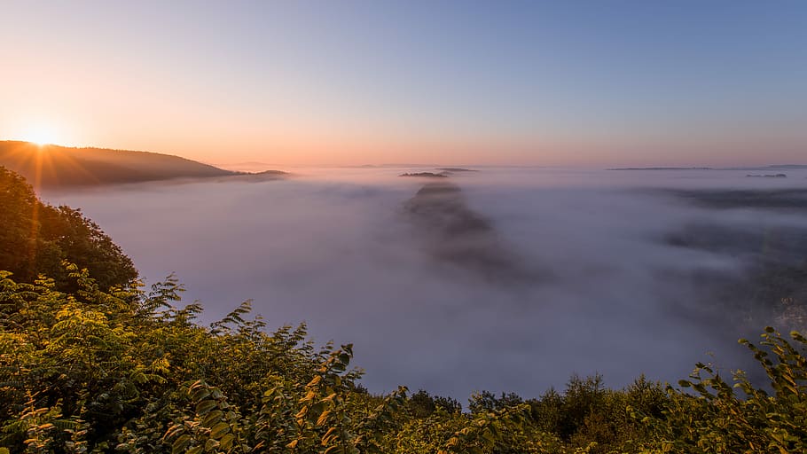 misty body of water during golden hour, photo of mountains covered with fog during golden HD wallpaper