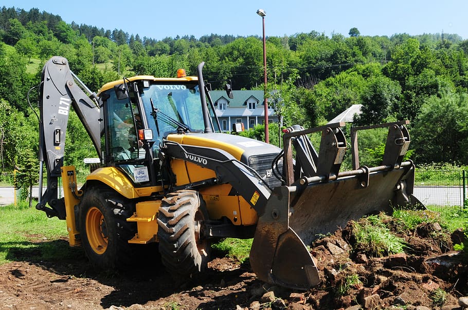 yellow and black Volvo backhoe near house and tree during daytime HD wallpaper