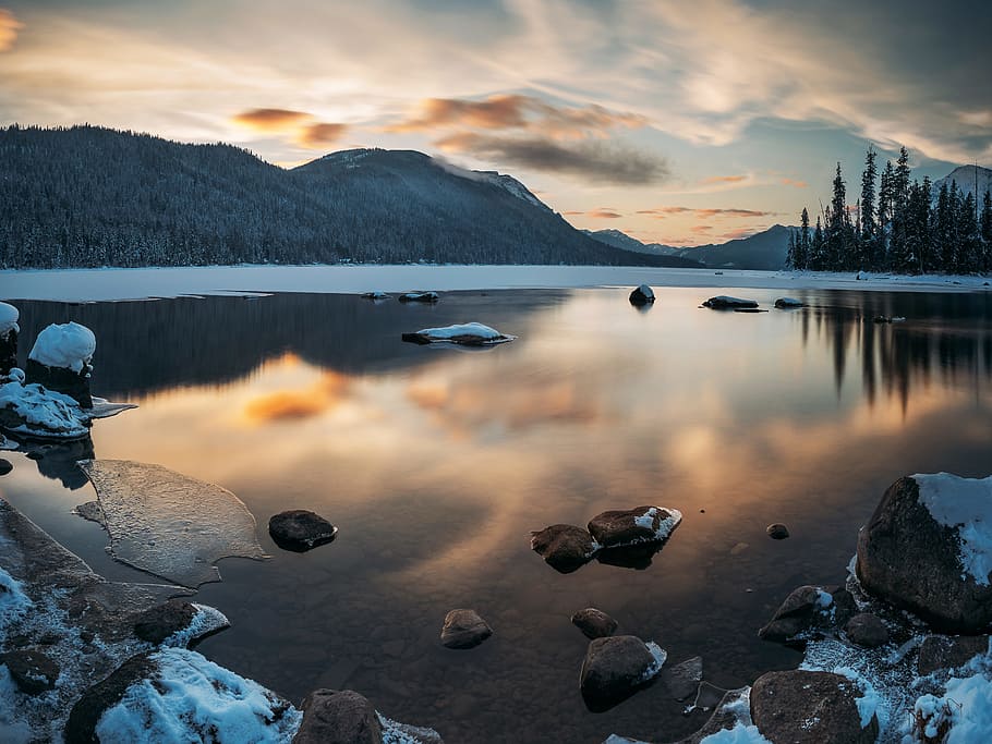 body of water under blue sky, photography of lake beside mountain at daytime HD wallpaper