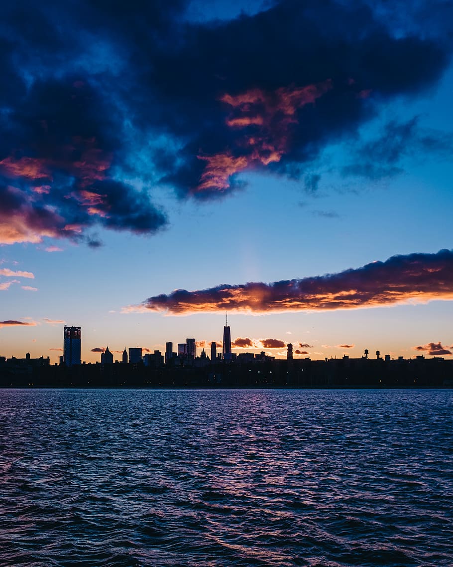 cityscape near body of water under partially cloudy skies, silhouette of city skyline between sky and sea during night time HD wallpaper