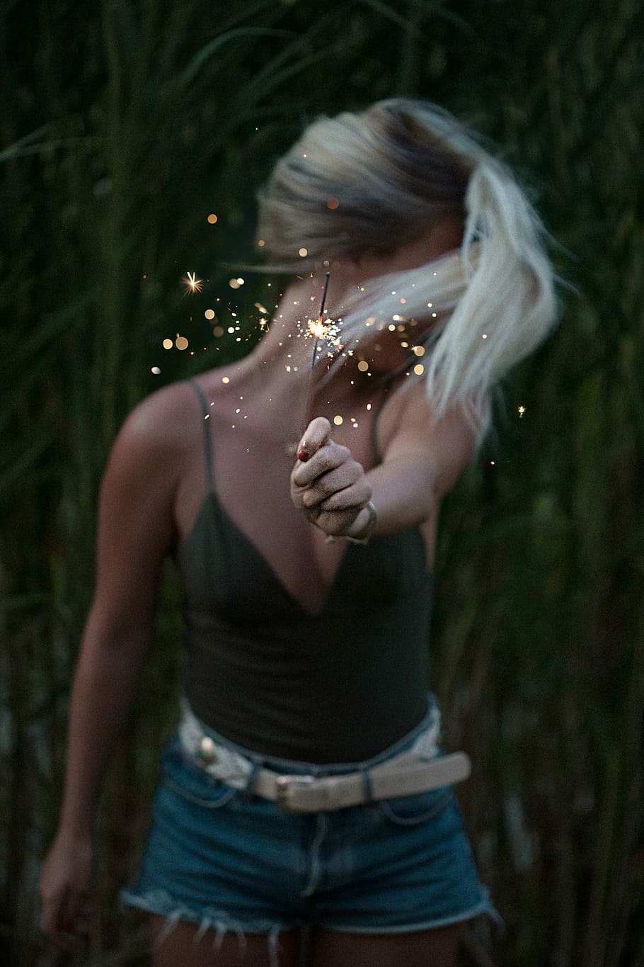 woman in black spaghetti-strap v-neck shirt holding a sparkler during nighttime HD wallpaper