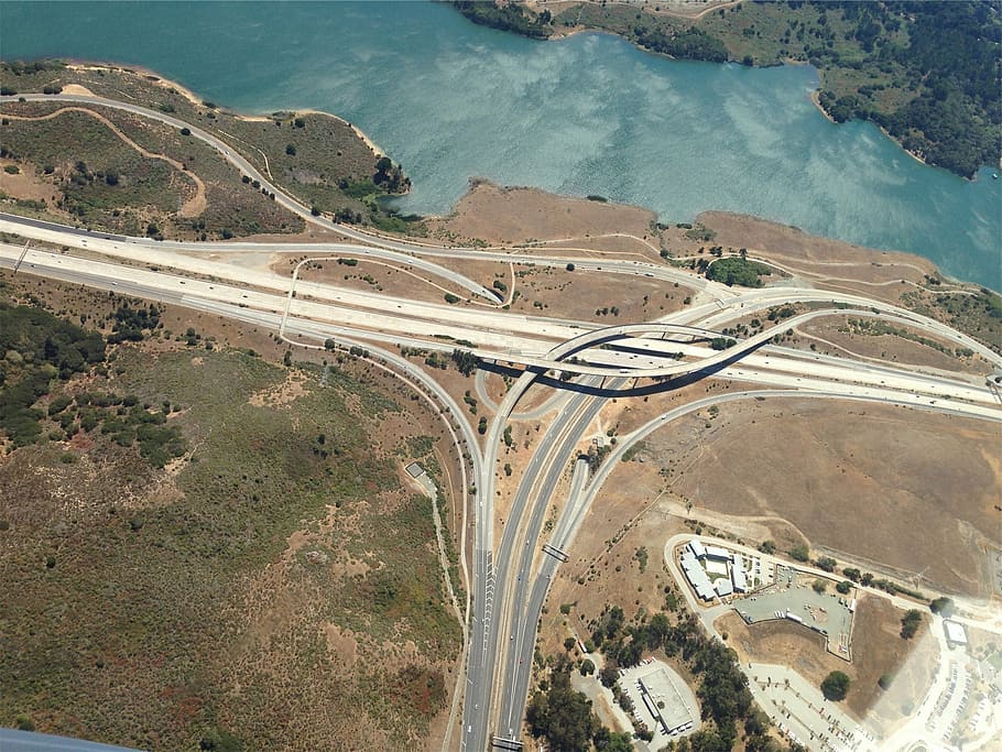 aerial photography of brown concrete road near body of water HD wallpaper