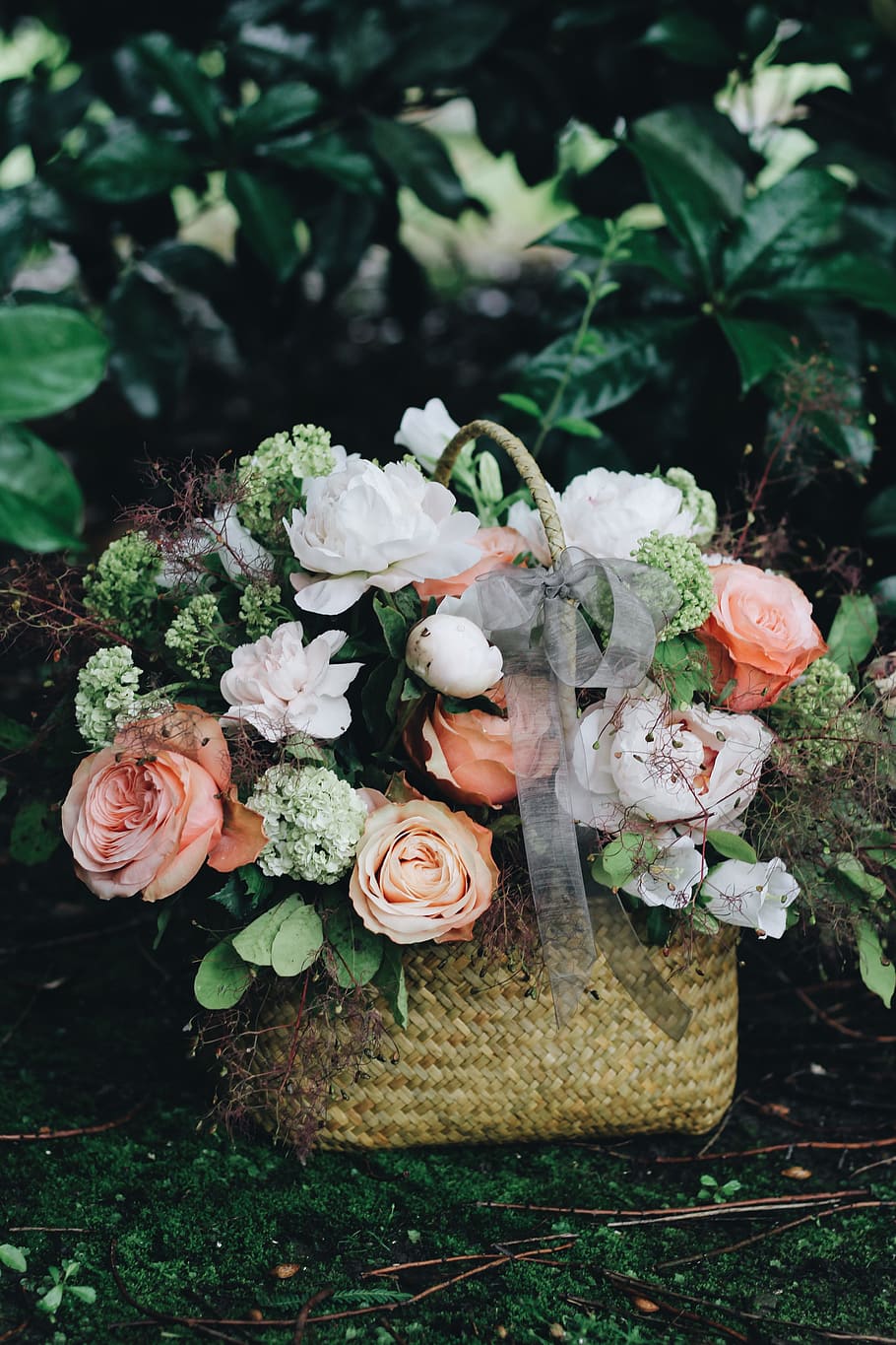 bouquet of white and pink flowers in basket, green, white, and pink petaled flowers in brown wicker basket