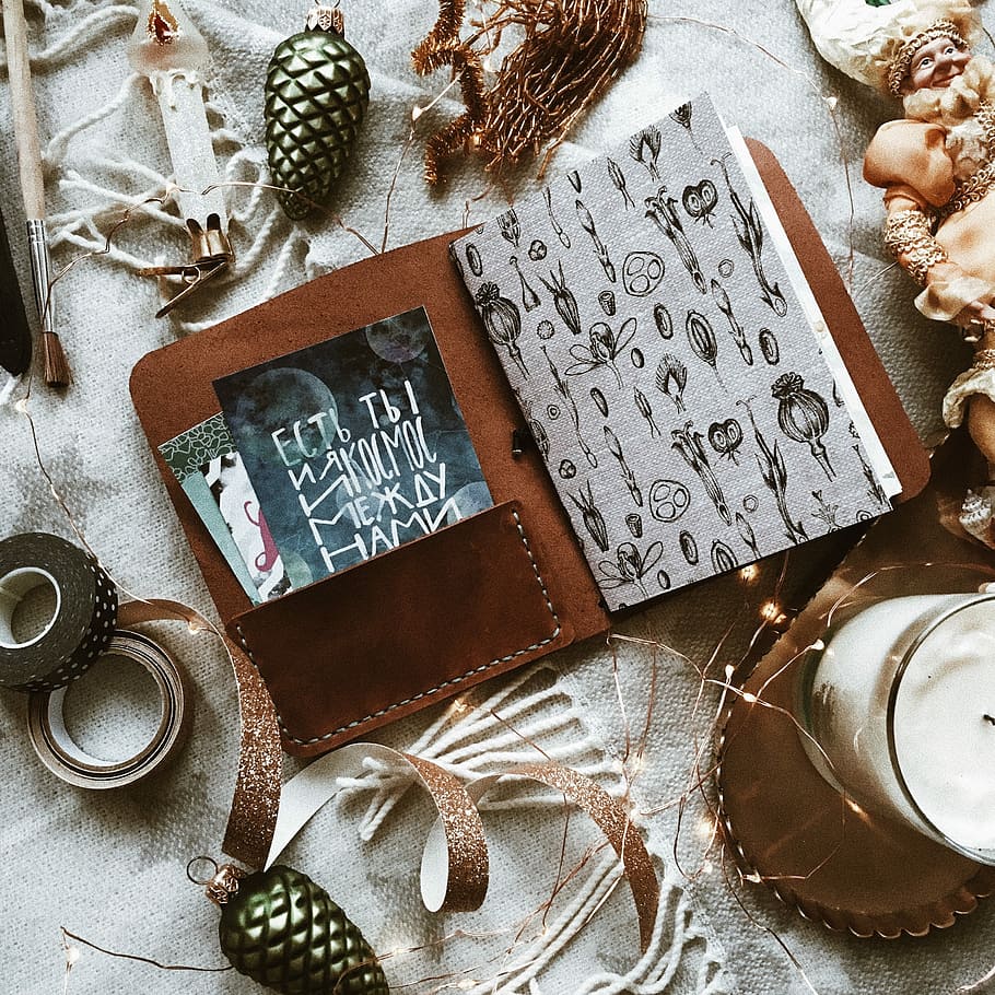 brown book holder, flat-lay photography of album beside ribbon tape and pine cone, HD wallpaper