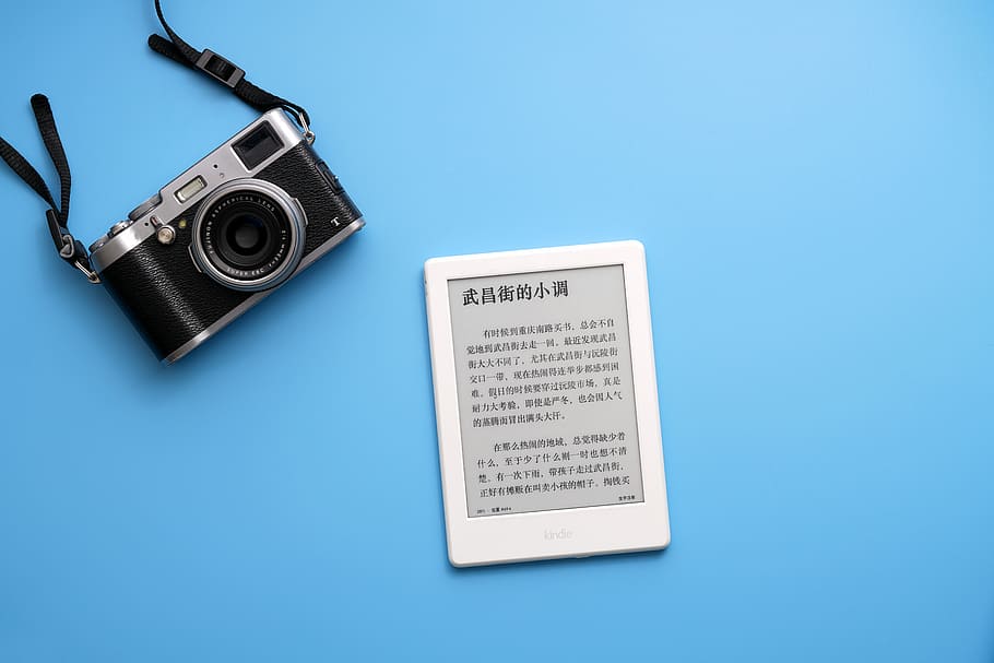 black SLR camera on and white e-book reader, black and gray camera beside white E-book reader HD wallpaper