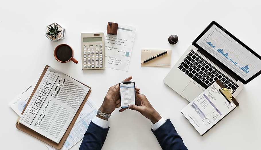 flat-lay photography of person holding space gray iPhone X beside macbook pro HD wallpaper