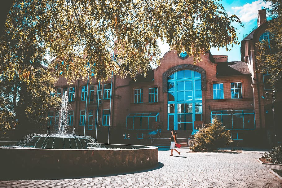 woman walking beside fountain and building during daytime, photo HD wallpaper