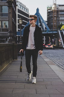 shallow focus photography of man holding DSLR camera, man holding Nikon DSLR camera walking on side of street HD wallpaper