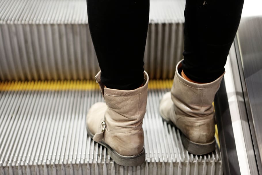 person wearing pair of beige leather boots on escalator, feet HD wallpaper