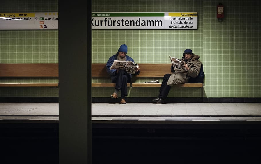 two men sitting on brown wooden bench reading magazines, two person sitting on brown bench reading newspapers HD wallpaper