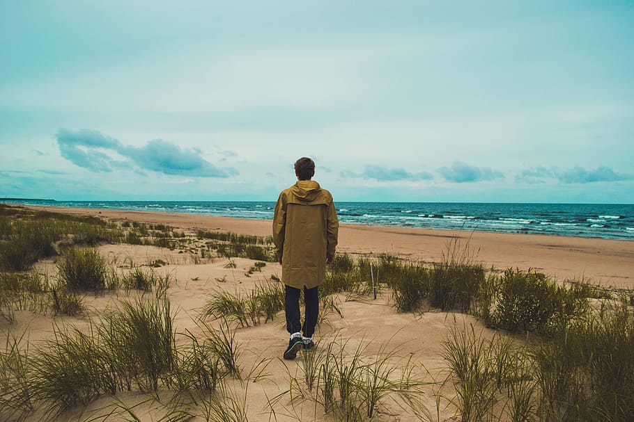 man in brown hooded jacket near sea under white clouds during daytime, HD wallpaper