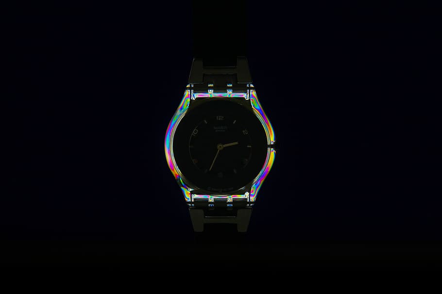 watch emitting lights, iridescent bezel watch against black background