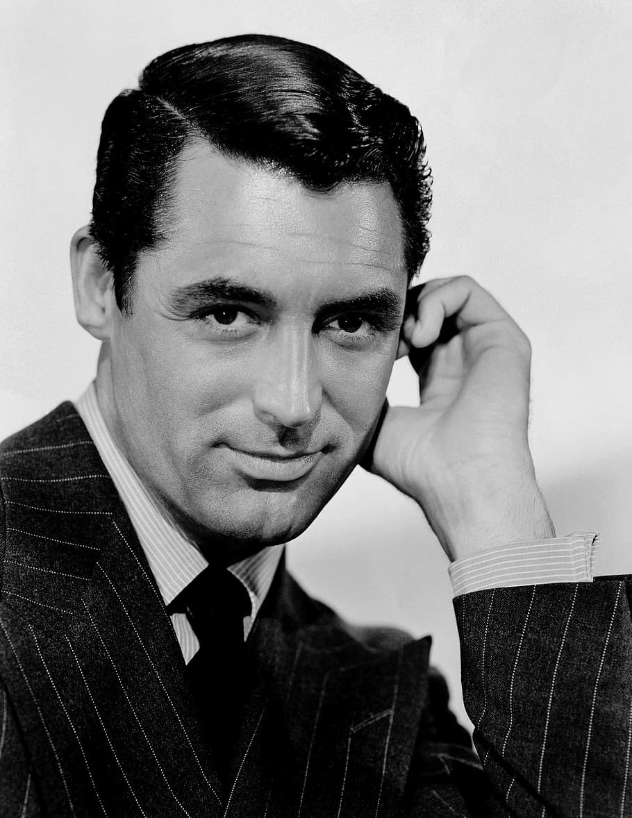 man wearing pinstripe suit with hand near left hand, gray scale