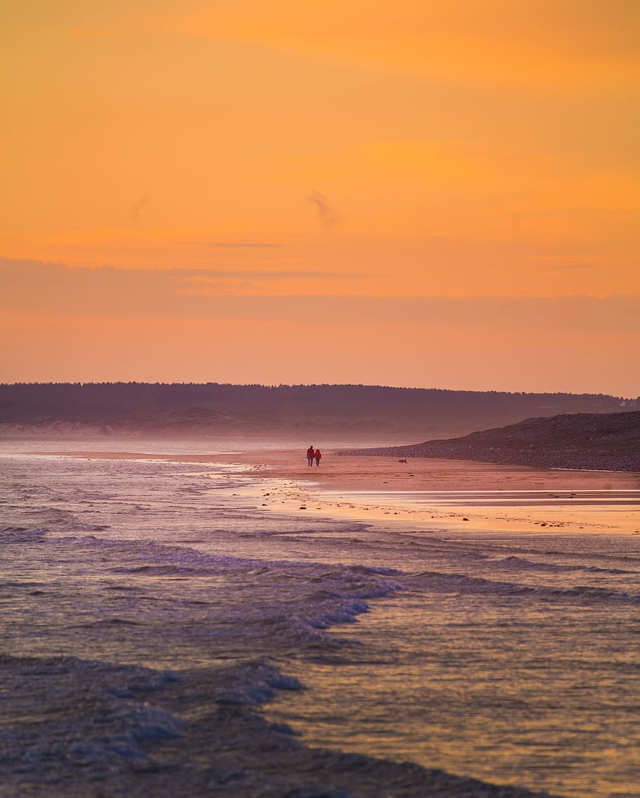 two person walking on beach sand, photo of two person walking on seashore during golden hour HD wallpaper