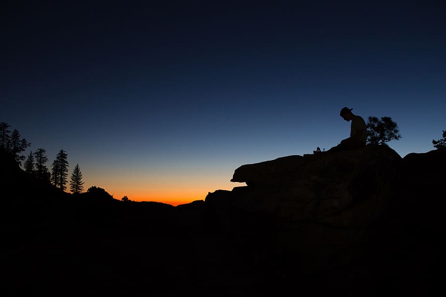 Silhouette of a man sitting on a rock at sunset in Yosemite Valley, USA