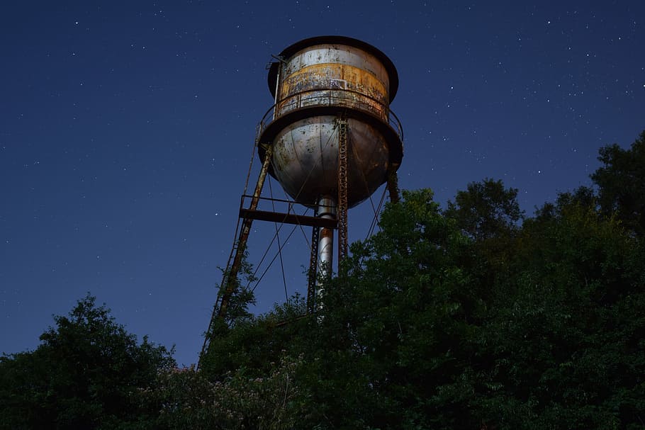 gray metal reservoir at daytime, gray water tank below green leafed trees during night time HD wallpaper