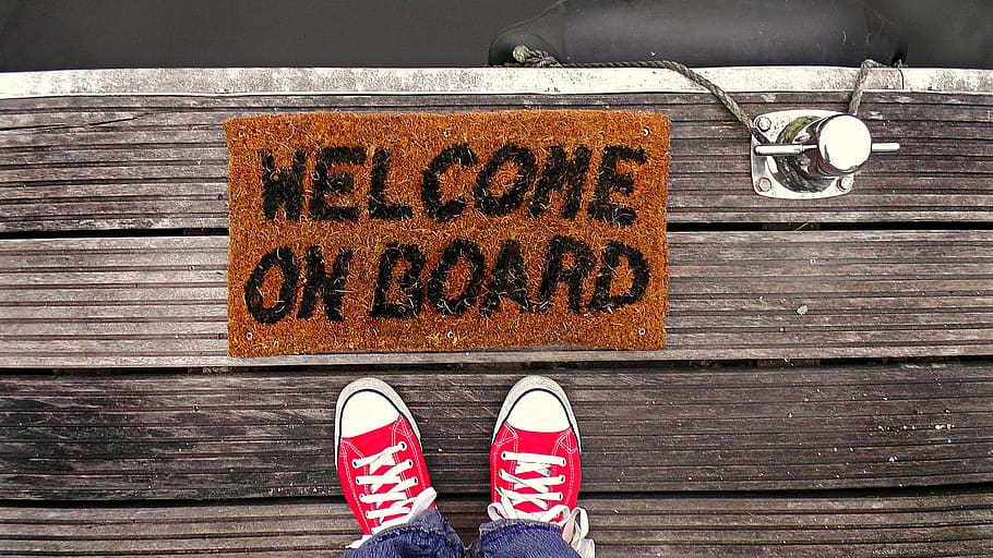 person standing beside welcome on board rug, dock, feet, footwear